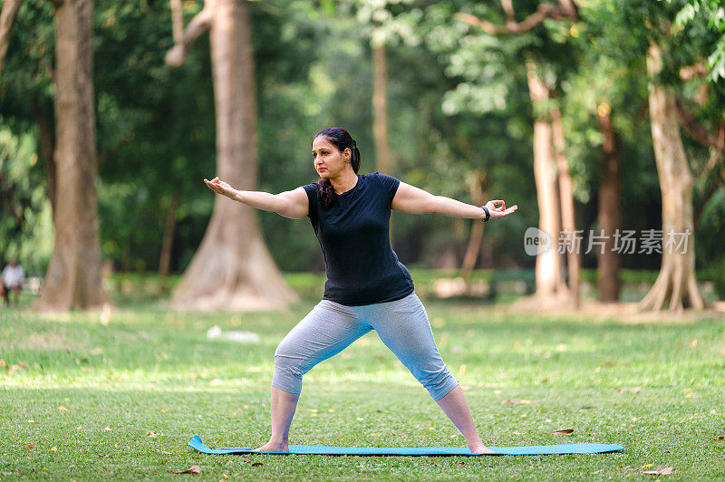 亚洲/印度女性在公园表演瑜伽体式，战士两种练习或Virabhadrasana II。